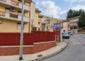 Ingresso della caserma dei carabinieri di San Cataldo, con recinzione e cancello rossi e l'insegna blu