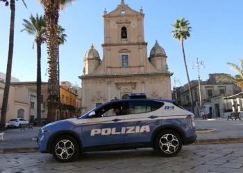 Auto della Polizia di Stato ferma in una piazza siciliana, con chiesa e palme sullo sfondo