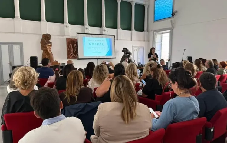 Pubblico sulle poltrone rosse della sala per l'incontro sulla storia del gospel a Modica, con la slide proiettata sullo schermo