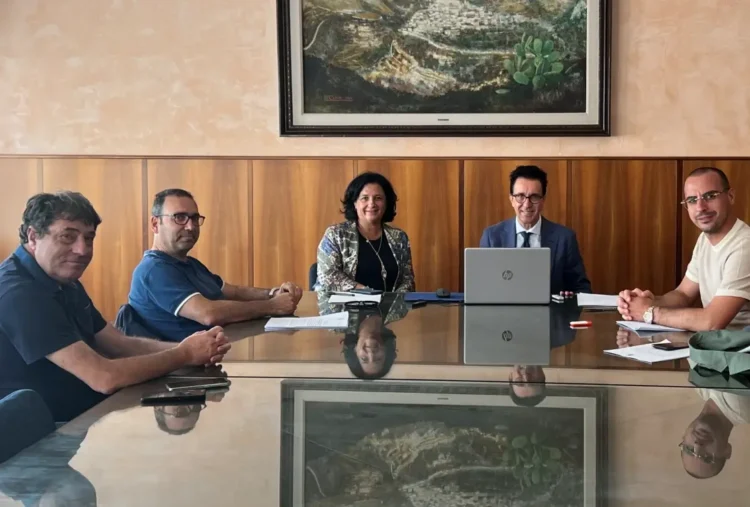 Cinque persone al tavolo della firma del contratto per i lavori stradali dell'aeroporto, la presidente al centro