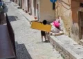 Fotogramma di una telecamera trappola: una persona abbandona un materasso e sacchi di rifiuti lungo una strada