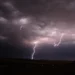 Temporali Sicilia con fulmini illuminano un cielo scuro sopra una zona rurale