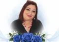 Ritratto di Teresa Di Giacomo, sorridente, con una composizione di rose blu simbolo del ricordo