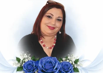 Ritratto di Teresa Di Giacomo, sorridente, con una composizione di rose blu simbolo del ricordo