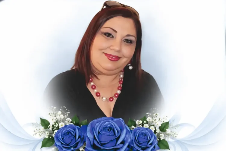Ritratto di Teresa Di Giacomo, sorridente, con una composizione di rose blu simbolo del ricordo