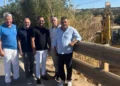 Cinque uomini in piedi lungo un guardrail nei pressi del torrente Trippatore, con un escavatore al lavoro sullo sfondo