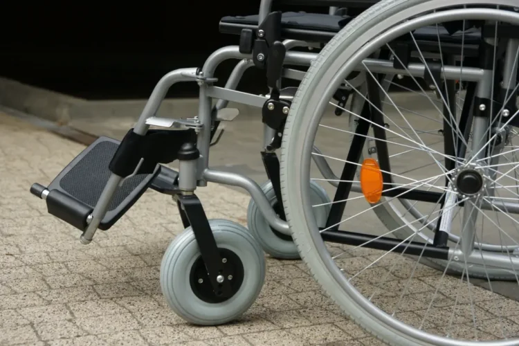 Dettaglio di una sedia a rotelle: ruote e pedana, simbolo del trasporto per persone con disabilità