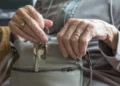 Mani di una persona anziana estraggono le chiavi da una borsa