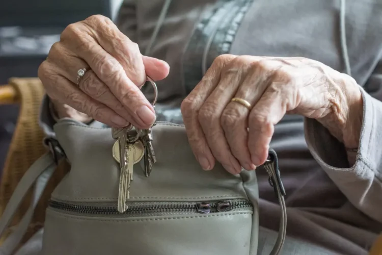 Mani di una persona anziana estraggono le chiavi da una borsa
