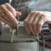 Mani di una persona anziana estraggono le chiavi da una borsa