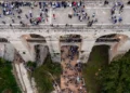 Vista dall'alto del Ponte Vecchio sulla vallata Santa Domenica a Ragusa, con persone sul ponte e nel fondovalle illuminato