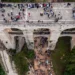 Vista dall'alto del Ponte Vecchio sulla vallata Santa Domenica a Ragusa, con persone sul ponte e nel fondovalle illuminato