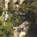 Sentiero con parapetti e lampioni nella Vallata Santa Domenica a Ragusa, tra alberi fitti e un ponte ad arcate in pietra