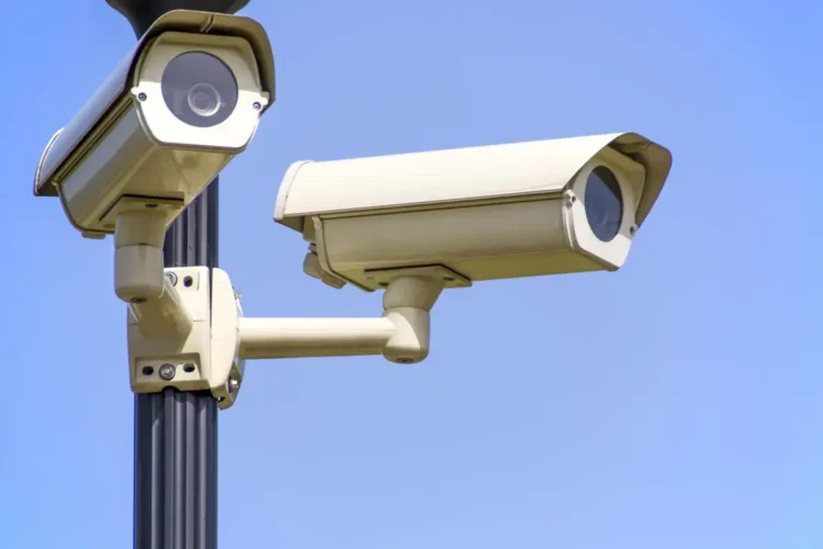 Due telecamere di videosorveglianza fissate su un palo, sullo sfondo cielo azzurro