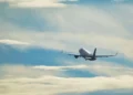 Aereo passeggeri bianco in volo dopo il decollo, con carrello estratto, tra nuvole chiare e cielo azzurro