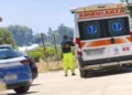 Ambulanza del 118 e auto della Polizia di Stato ferme su una strada, con un soccorritore in divisa ad alta visibilità
