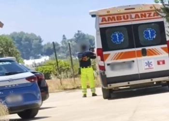 Ambulanza del 118 e auto della Polizia di Stato ferme su una strada, con un soccorritore in divisa ad alta visibilità