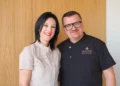 Andrea Giannone e Alice in divisa da pasticceria, sorridenti davanti a una parete rivestita in legno chiaro
