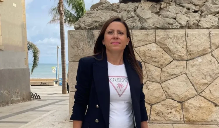Antonella Salerno, nuova presidente della Pro Loco Mazzarelli, in giacca blu davanti a un muro di pietra vicino al mare