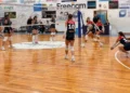 Partita di volley femminile a Comiso: una giocatrice si allunga in bagher per ricevere il pallone, le compagne la guardano