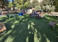 Area giochi della villa comunale di Comiso con prato sintetico, struttura con scivolo, giochi a forma di animale e panchine