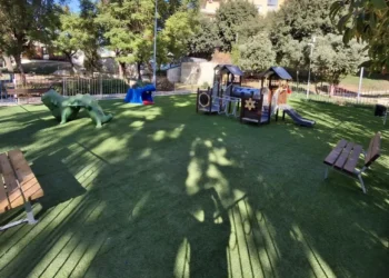 Area giochi della villa comunale di Comiso con prato sintetico, struttura con scivolo, giochi a forma di animale e panchine