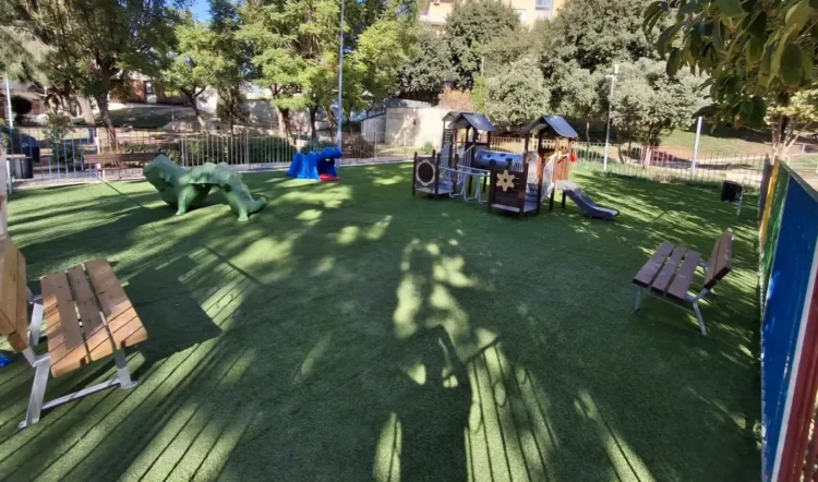 Area giochi della villa comunale di Comiso con prato sintetico, struttura con scivolo, giochi a forma di animale e panchine