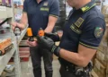 Due finanzieri in un magazzino di Misterbianco mostrano lanterne di Halloween a forma di teschio e zucca tra scaffali e scatoloni