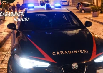 Gazzella dei carabinieri con i lampeggianti blu accesi di notte, ferma su una strada lastricata nella zona di Modica