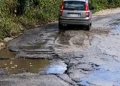 Auto grigia su un tratto dello stradale di Alcerito con asfalto sbriciolato, buche piene d’acqua e crepe lungo la carreggiata