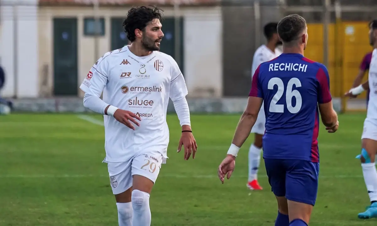 Calciatore del Modica in maglia bianca numero 29 in campo durante una partita, accanto a un avversario in maglia blu e rossa