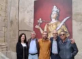 Cinque persone in posa nel cortile della chiesa di Santa Lucia a Modica, davanti a un pannello con la statua della santa