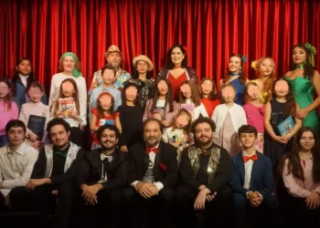 Attori e piccoli allievi della compagnia Godot di Ragusa in posa sul palco davanti a un sipario rosso, alcuni con libri in mano