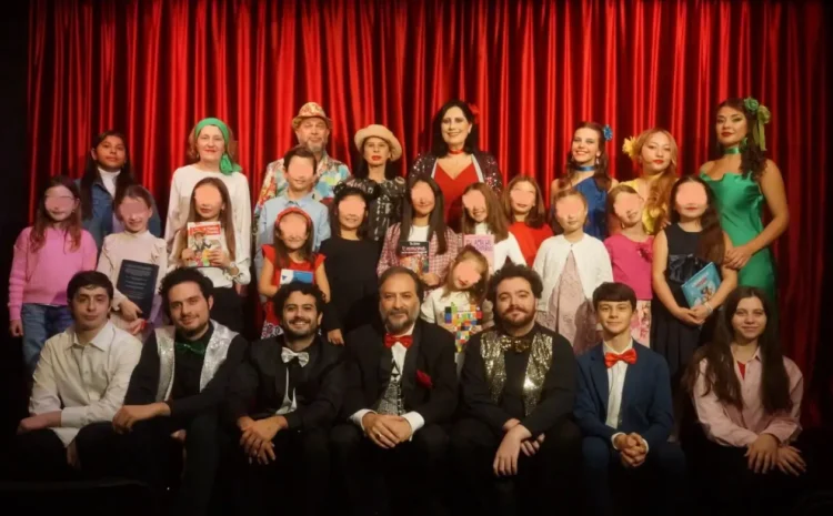 Attori e piccoli allievi della compagnia Godot di Ragusa in posa sul palco davanti a un sipario rosso, alcuni con libri in mano
