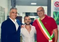 Daniele Spadola sorridente tra due uomini all’inaugurazione della sua palestra a Ispica, uno con la fascia tricolore
