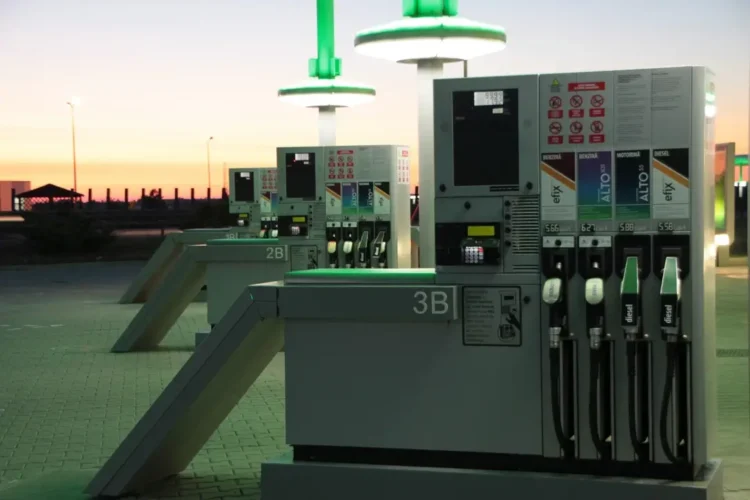 Colonnine di un distributore di carburanti al tramonto, con pistole diesel e benzina e i prezzi al litro esposti