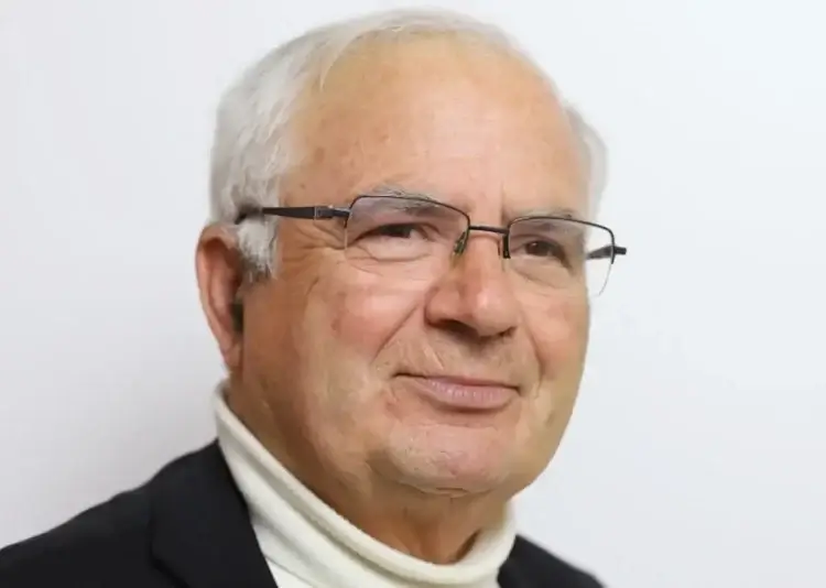 Don Giovanni Mandarà, sacerdote della diocesi di Ragusa, ritratto con occhiali, maglia bianca a collo alto e giacca scura