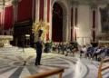 Un uomo parla al microfono nel Duomo di San Giorgio a Ragusa, davanti al pubblico seduto per il festival organistico