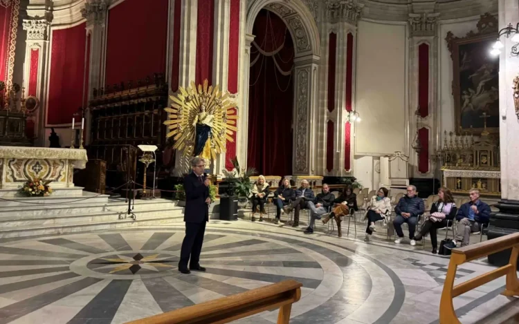 Un uomo parla al microfono nel Duomo di San Giorgio a Ragusa, davanti al pubblico seduto per il festival organistico