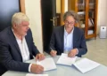 Due uomini in giacca firmano documenti a un tavolo di vetro: incarico per la Psichiatria 1 Ragusa-Vittoria