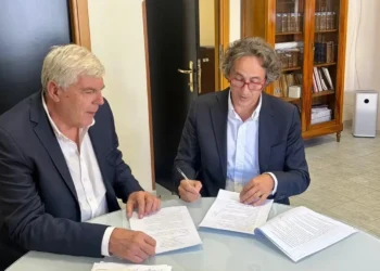 Due uomini in giacca firmano documenti a un tavolo di vetro: incarico per la Psichiatria 1 Ragusa-Vittoria