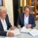Due uomini in giacca firmano documenti a un tavolo di vetro: incarico per la Psichiatria 1 Ragusa-Vittoria