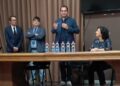 Documenti firmati su un tavolo, sullo sfondo l’aeroporto di Comiso