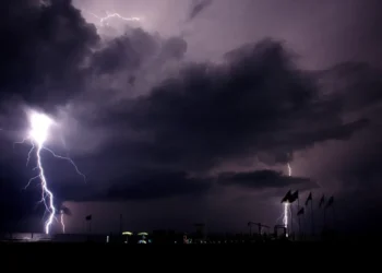 Fulmini cadono sul mare di notte vicino a uno stabilimento balneare, cielo temporalesco: allerta meteo in Sicilia