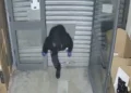 Uomo incappucciato con guanti blu entra strisciando sotto una serranda sollevata nel furto da Bruno Euronics a Modica