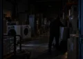 Uomo di spalle tra lavatrici e frigoriferi in un magazzino al buio, scena di furto. Immagine generata con intelligenza artificiale.