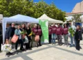 Soci del GAS Mazzarelli in felpa bordeaux posano in piazza tra i gazebo, con ortaggi freschi e borse della spesa