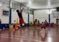 Giocatore del Giarratana Volley in maglia blu e pantaloncini rossi salta per la battuta in una palestra durante una gara
