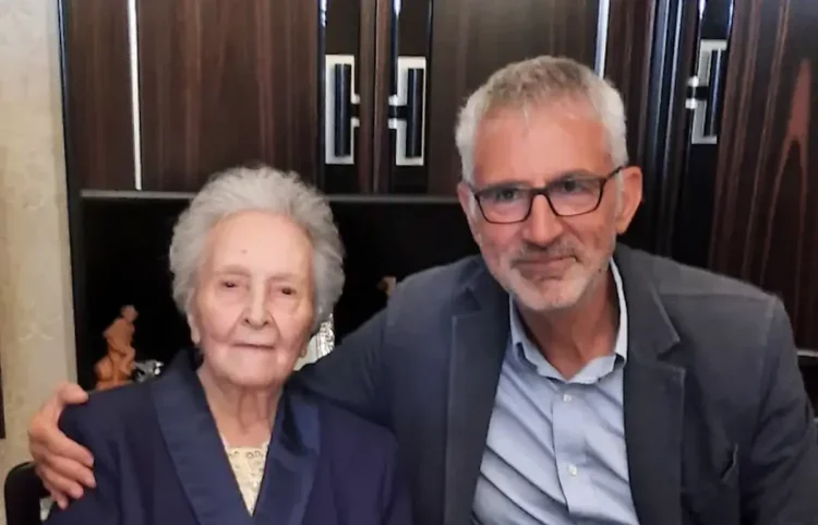 Giuseppa Gurrieri, 100 anni, seduta accanto al sindaco Peppe Cassì che la cinge con un braccio, davanti a un mobile scuro