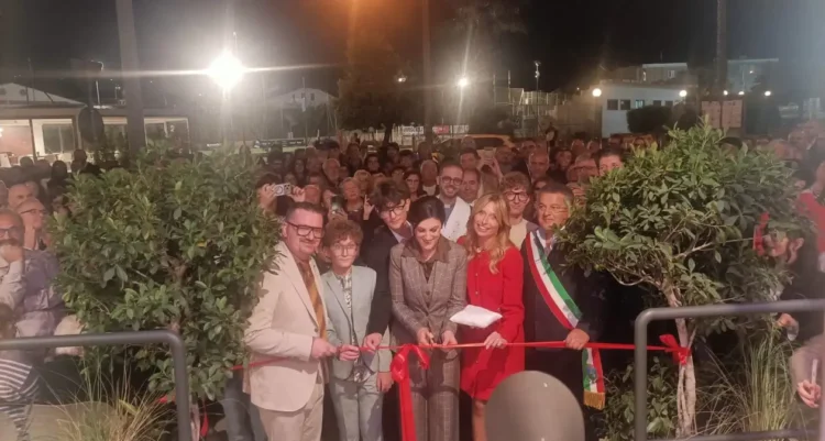 Taglio del nastro rosso all’ingresso della nuova pasticceria a Scicli, di sera, con il sindaco in fascia tricolore e il pubblico